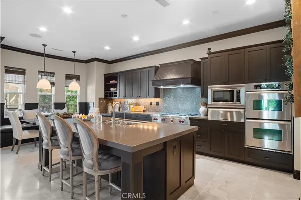a large kitchen with stainless steel appliances wooden floor dining table and chairs