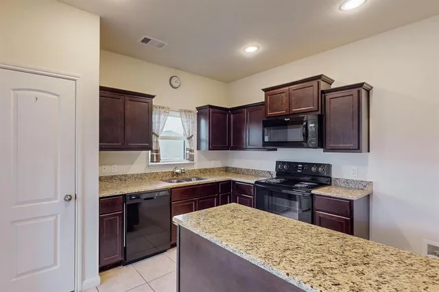 a kitchen with stainless steel appliances granite countertop wooden cabinets stove and refrigerator