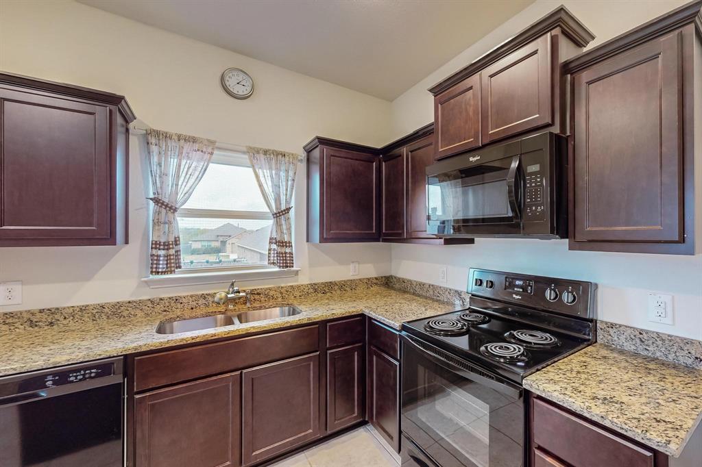 10 Kramer Court Sanger, TX 76266 - Photo 13 of 38 a kitchen with granite countertop a sink stove and refrigerator
