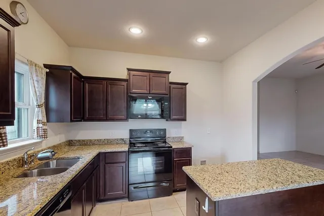 a kitchen with granite countertop a sink and a stove top oven with wooden floor