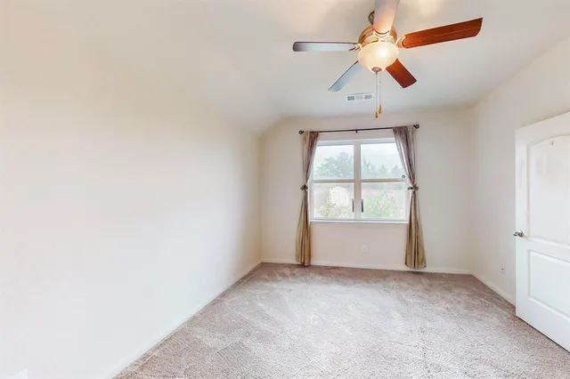 an empty room with a window and a ceiling fan
