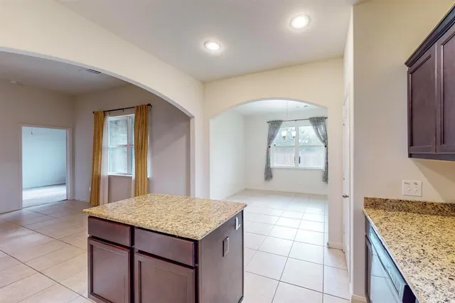 a kitchen with kitchen island granite countertop a sink and a stove