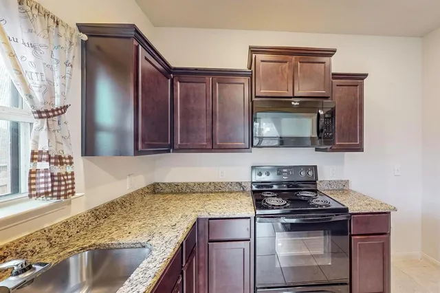 a kitchen with granite countertop stainless steel appliances a stove sink and microwave