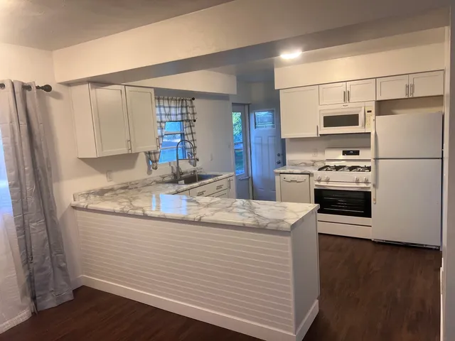 a kitchen with stainless steel appliances granite countertop a sink a stove a refrigerator and island with wooden floor