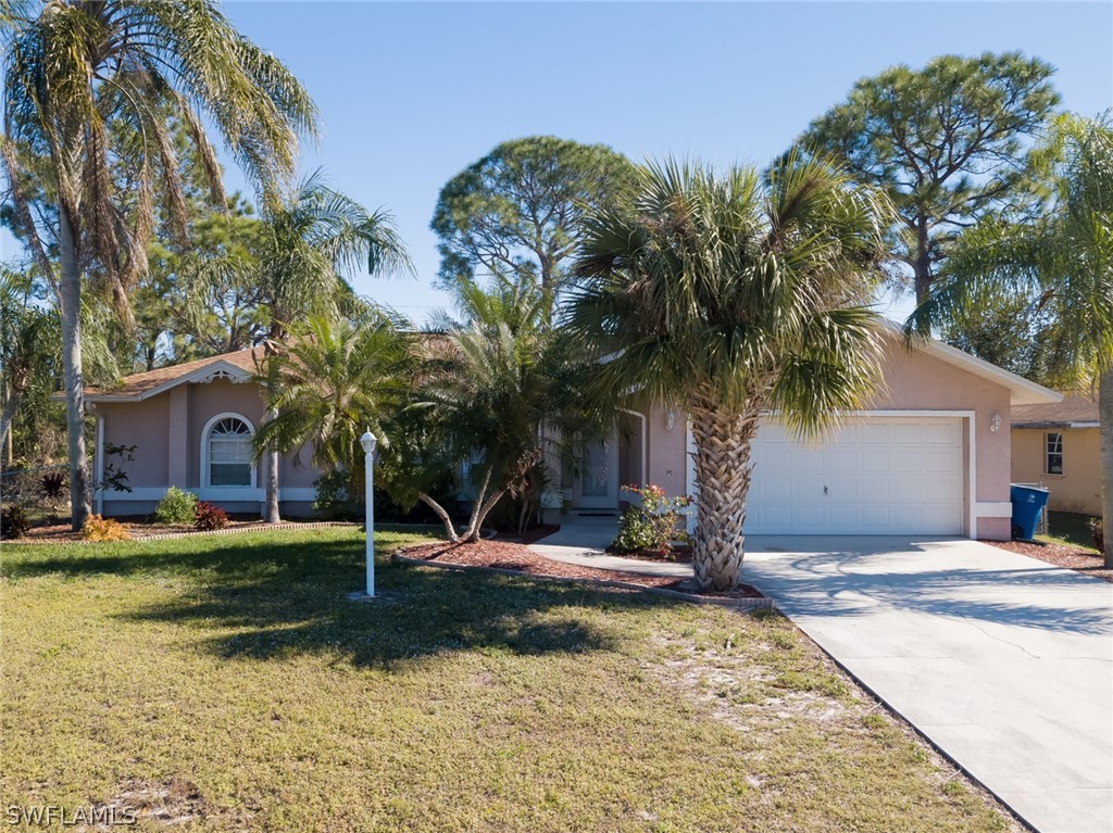 17525 Lee Road Fort Myers, FL 33967 - Photo 1 of 24 a front view of a house with a yard and palm trees