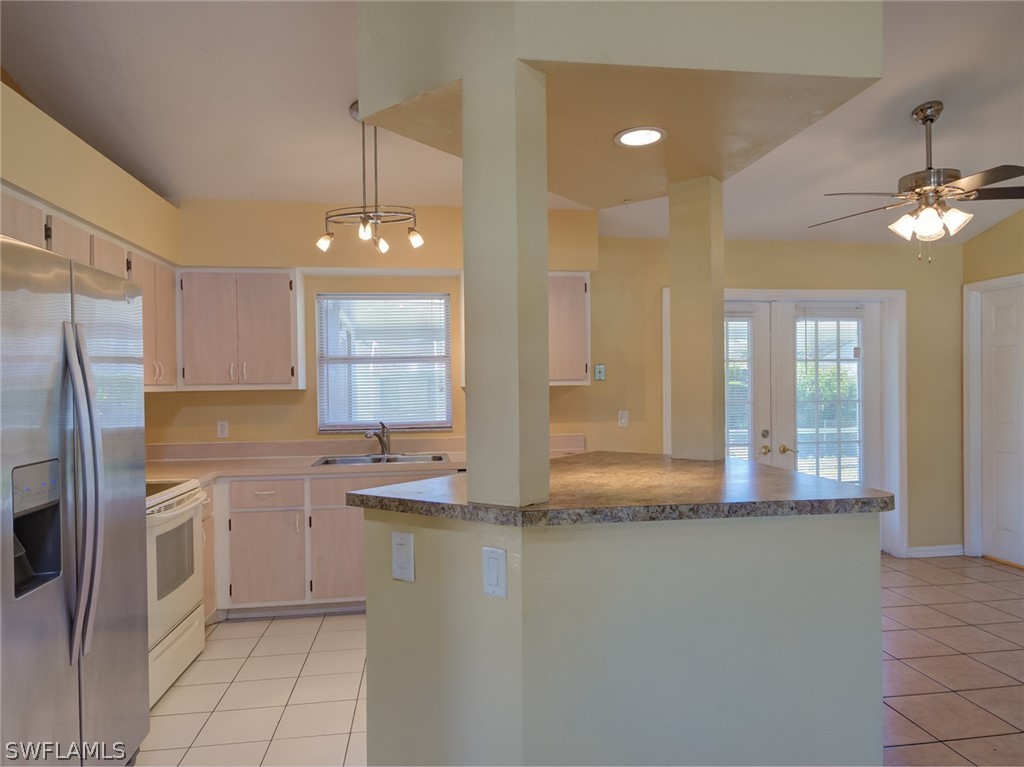 17525 Lee Road Fort Myers, FL 33967 - Photo 4 of 24 a kitchen with stainless steel appliances granite countertop a refrigerator a sink dishwasher a stove and white countertops with wooden floor