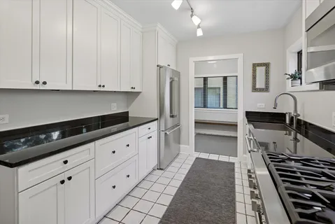 a kitchen with granite countertop a stove and white cabinets