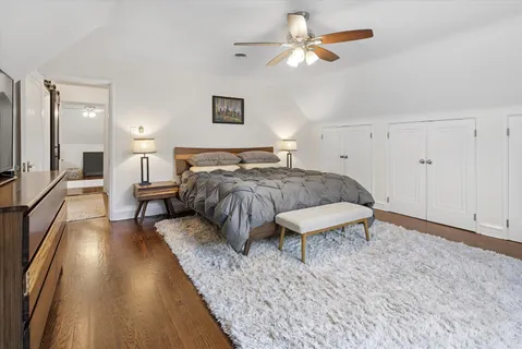 a spacious bedroom with a bed a chandelier and a mirror