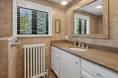 a bathroom with a granite countertop sink and a window