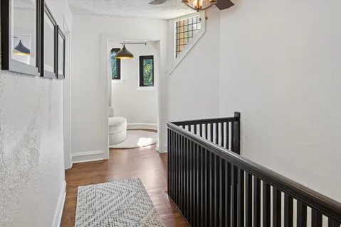 a view of a hallway with wooden floor and a bathroom