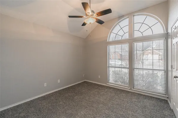 an empty room with windows and fan