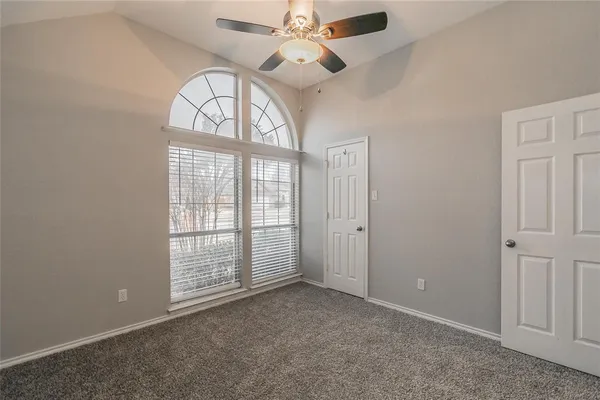 en empty room with windows and ceiling fan