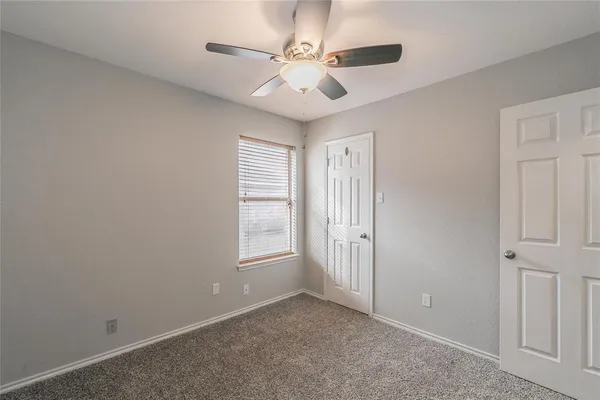 an empty room with windows and ceiling fan
