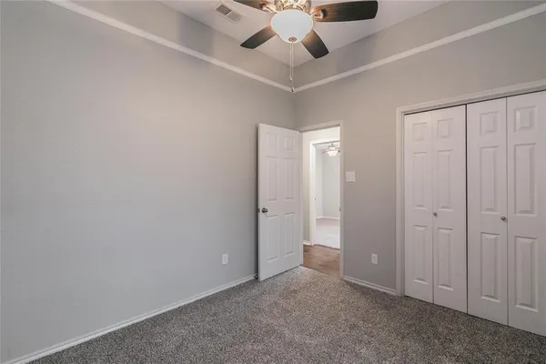an empty room with a ceiling fan and carpet