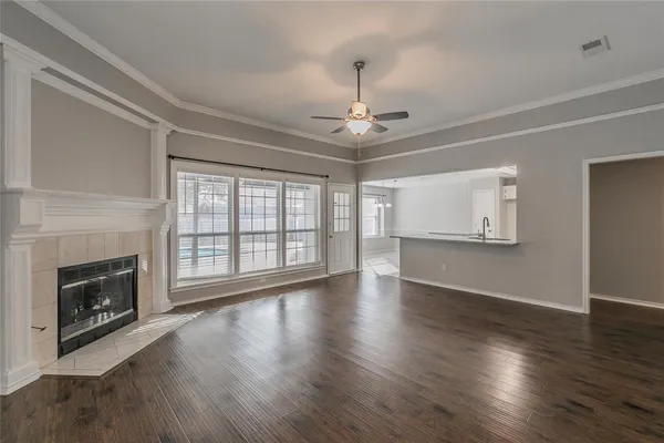 a view of an empty room with wooden floor fireplace and a window