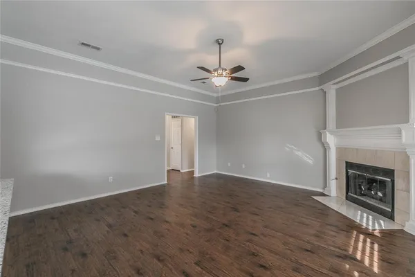 a view of an empty room with wooden floor fireplace and a window