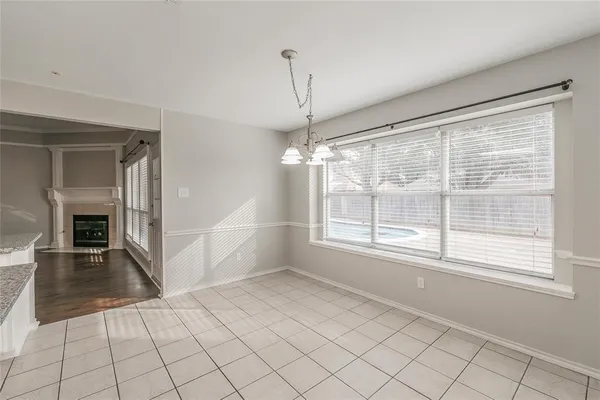 a view of an empty room with wooden floor and a kitchen
