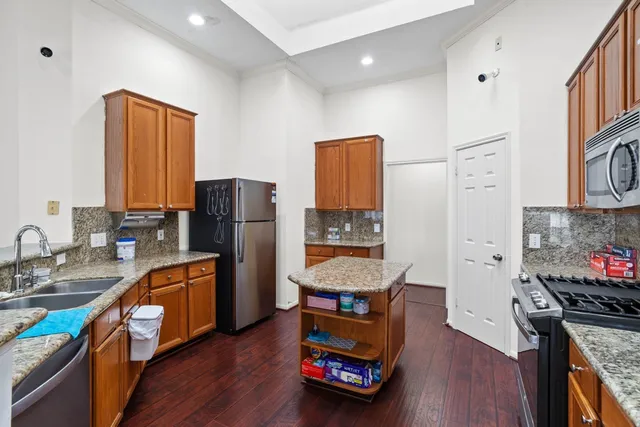 a kitchen with stainless steel appliances granite countertop a refrigerator a stove top oven a sink dishwasher and wooden floor