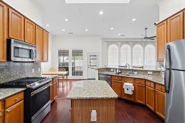 a kitchen with stainless steel appliances granite countertop wooden cabinets a stove top oven and granite counter tops