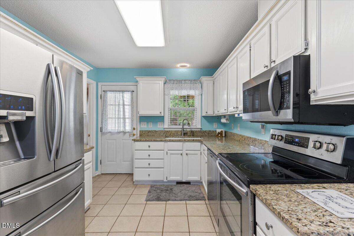 4317 South Mountain Drive Raleigh, NC 27603 - Photo 14 of 57 a kitchen with stainless steel appliances granite countertop a stove a sink and a refrigerator