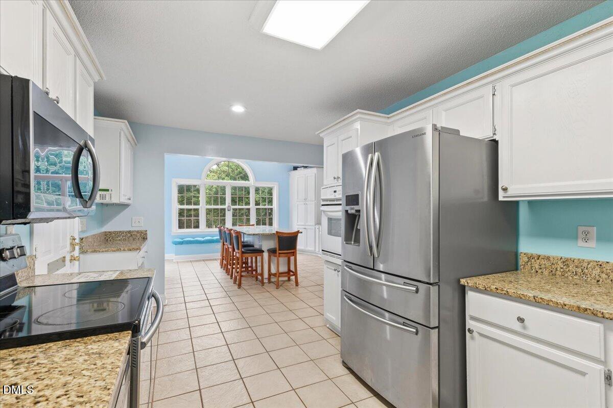 4317 South Mountain Drive Raleigh, NC 27603 - Photo 15 of 57 a kitchen with stainless steel appliances granite countertop a refrigerator and a stove top oven