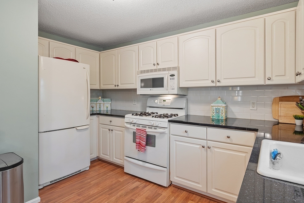 187 Turnpike Road, Unit 187 Chelmsford, MA 01824 - Photo 3 of 42 a kitchen with white cabinets and white appliances