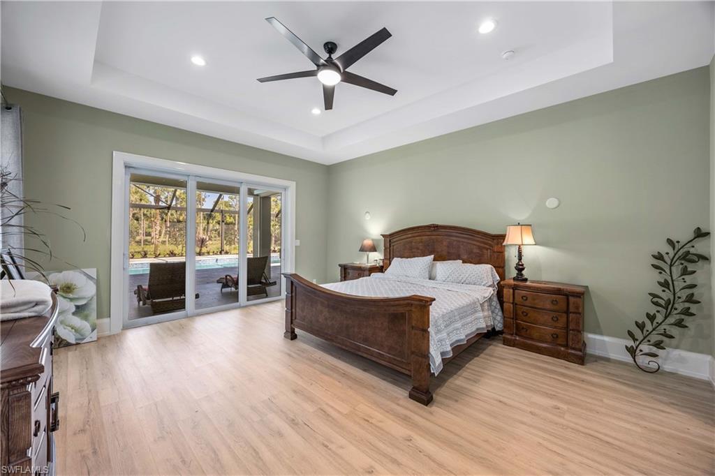 4885 Tamarind Ridge Drive Naples, FL 34119 - Photo 16 of 39 a spacious bedroom with a bed a chandelier and a window