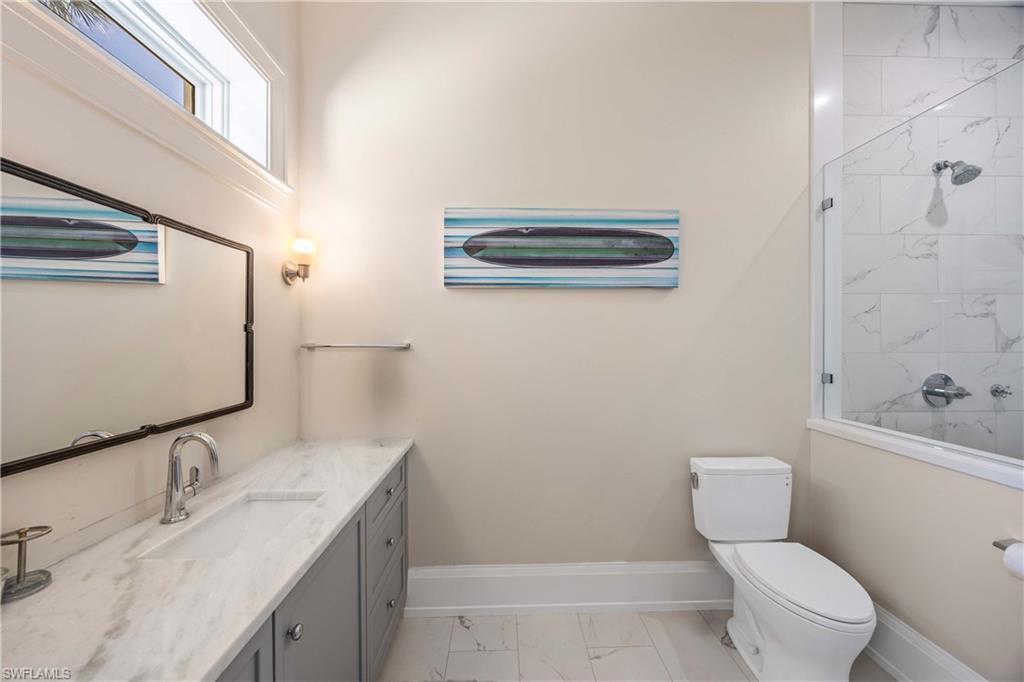 4885 Tamarind Ridge Drive Naples, FL 34119 - Photo 23 of 39 a bathroom with a granite countertop toilet a sink and a mirror