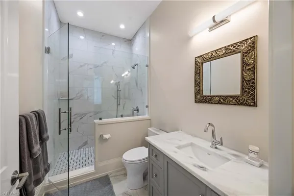 a bathroom with a granite countertop sink mirror vanity and toilet