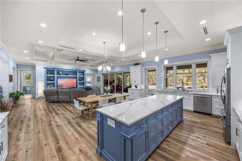 4885 Tamarind Ridge Drive Naples, FL 34119 - Photo 10 of 39 a large living room with stainless steel appliances kitchen island granite countertop a large kitchen island a stove a sink a refrigerator and a living room view