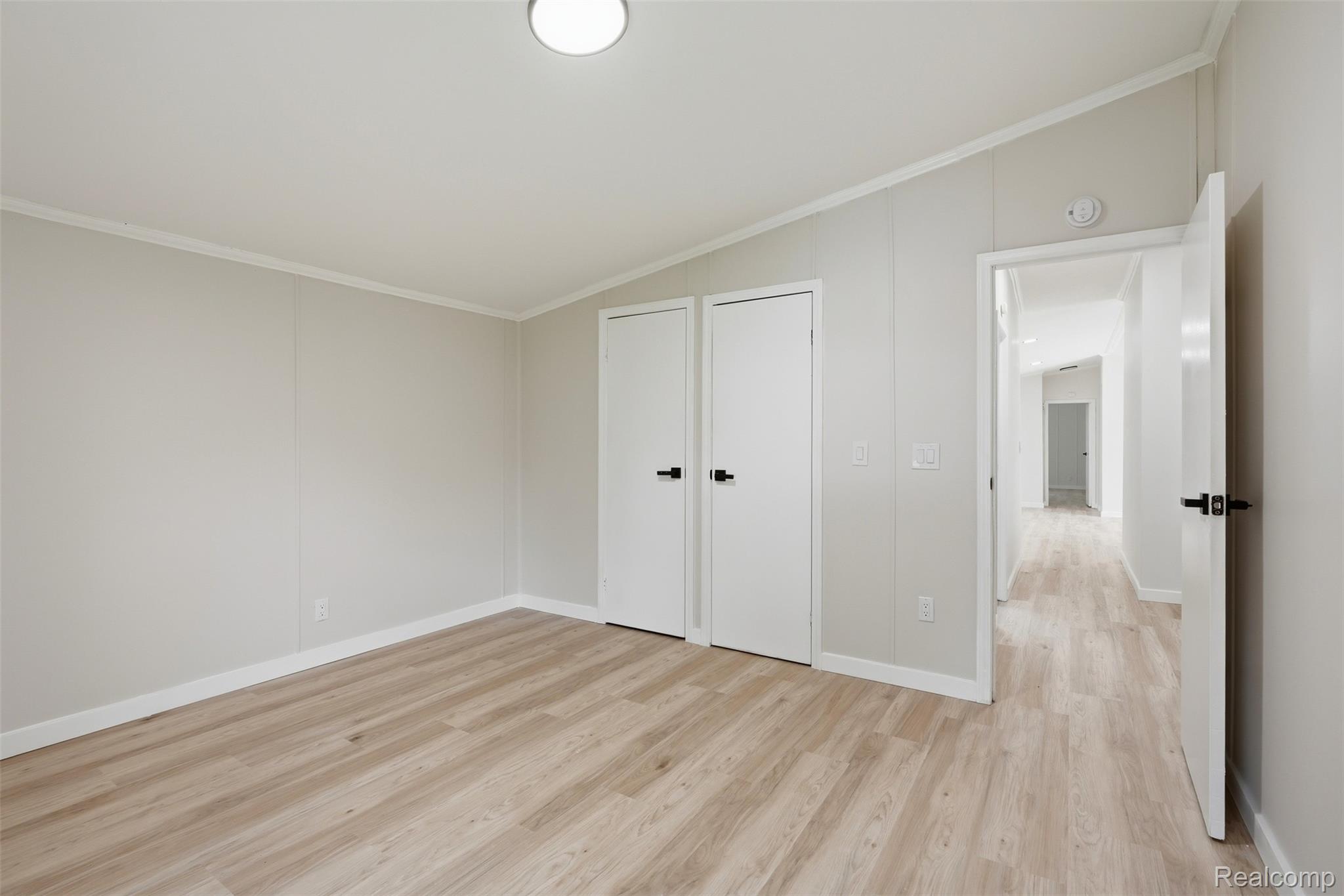 4420 Dublin Road Burton, MI 48529 - Photo 25 of 56 Bedroom featuring light wood-finish flooring, white baseboards, and two white doors with matte black hardware