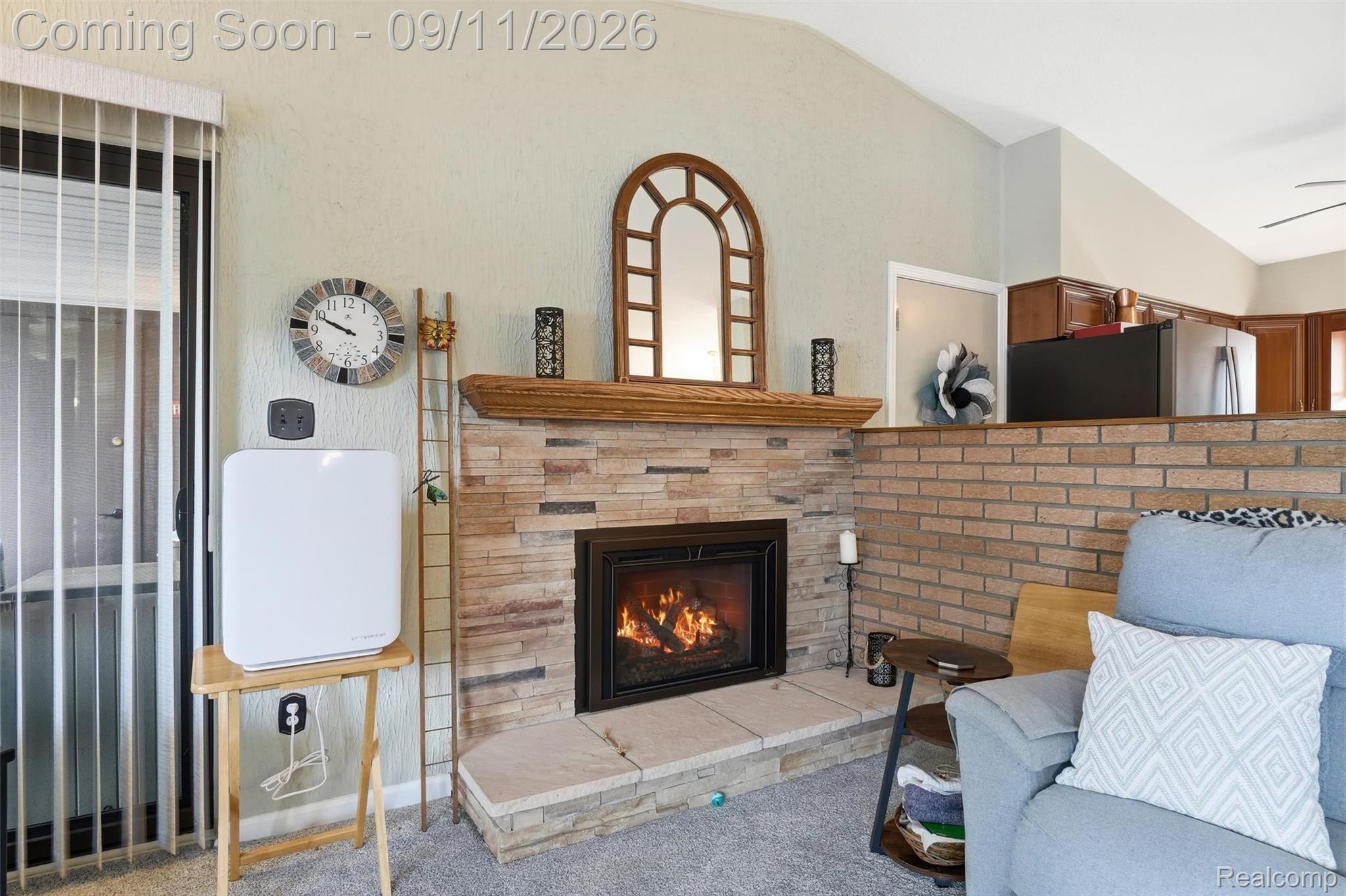 16799 Farmington Road Livonia, MI 48154 - Photo 20 of 71 Stone-clad fireplace with a wood mantel, vaulted ceiling, and an open-concept partition wall