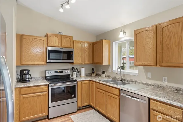 a kitchen with stainless steel appliances granite countertop a sink a stove and cabinets
