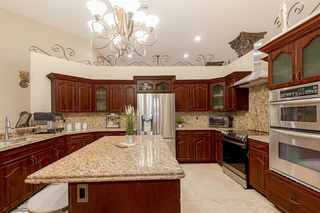 Davie Davie, FL 33330 - Photo 12 of 57 a kitchen with kitchen island granite countertop a sink stainless steel appliances wooden cabinets and counter space