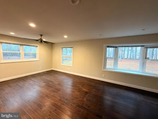 an empty room with wooden floor and windows