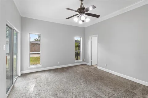an empty room with windows and fan