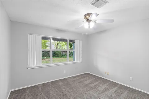 an empty room with a window and a fan