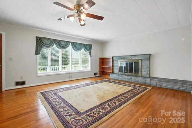 a view of an empty room with window and wooden floor