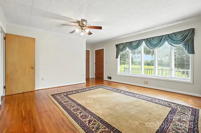 a view of an empty room with a window and wooden floor
