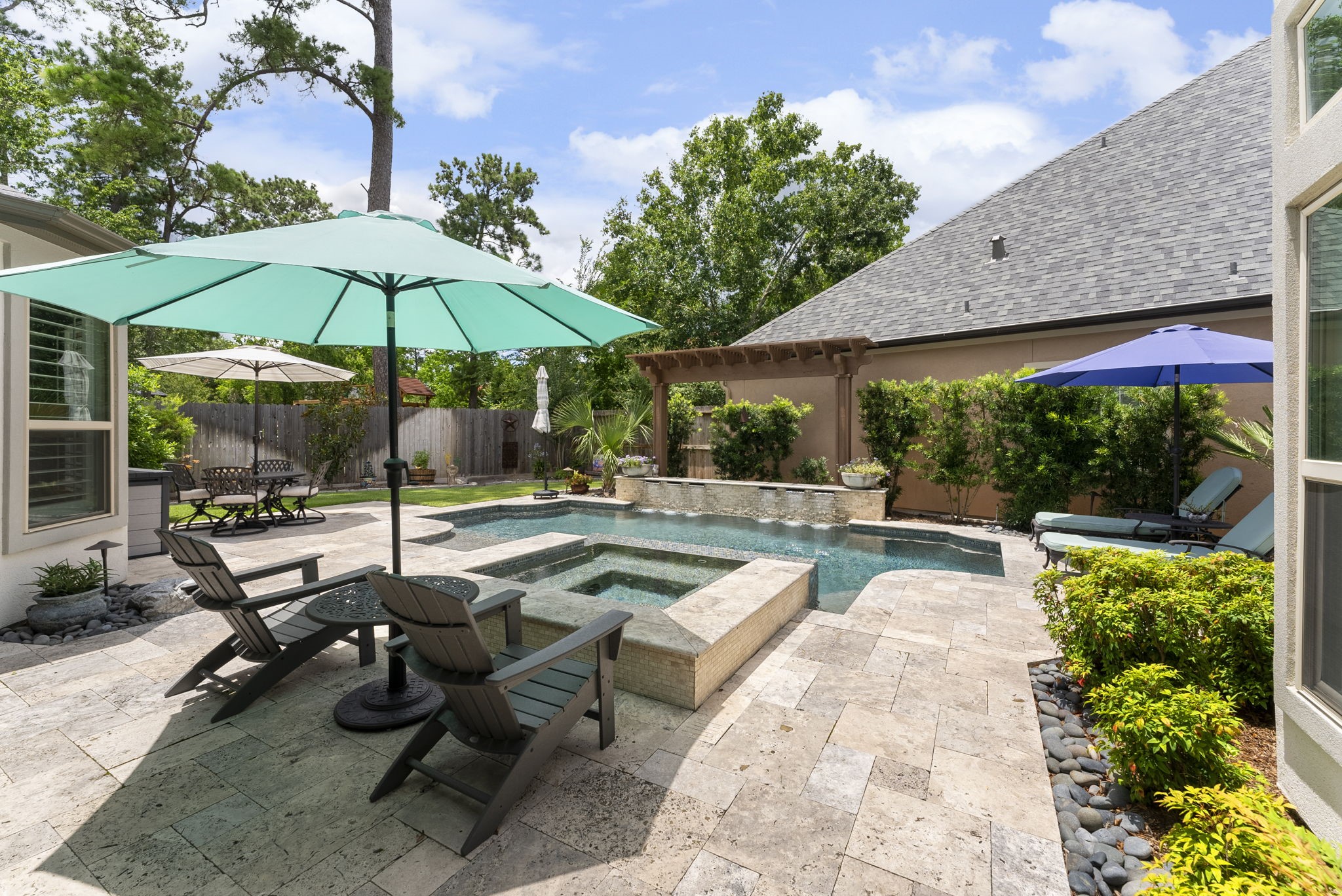 25607 Muirfield Bend Court Spring, TX 77389 - Photo 25 of 30 Resort-style outdoor living designed for year-round enjoyment, featuring a custom pool and spa, expansive travertine decking, multiple lounging areas, and exceptional privacy.
