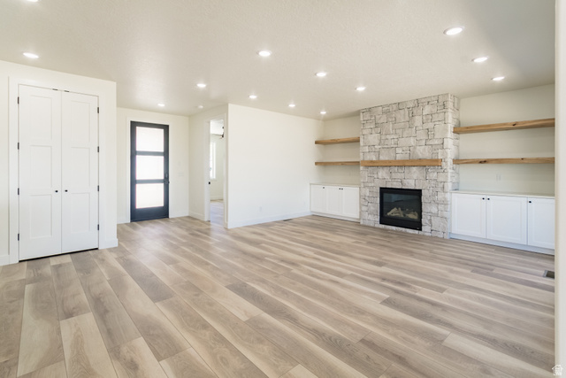 3322 250 S Street Vernal, UT 84078 - Photo 3 of 37 Spacious living area featuring light wood-finish flooring, a stone fireplace with a wood mantel, built-in shelving, white cabinetry, and recessed lighting