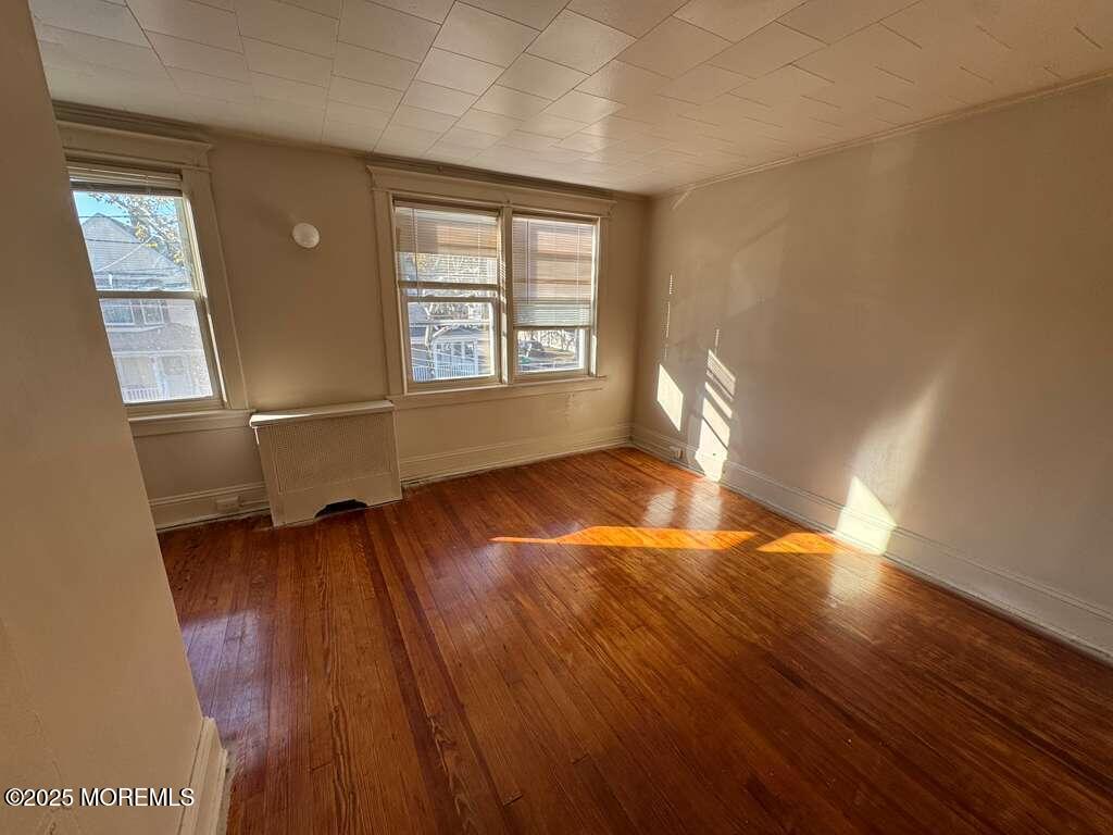 110 Rector Street, Unit 2 Perth Amboy, NJ 08861 - Photo 6 of 6 an empty room with wooden floor and windows