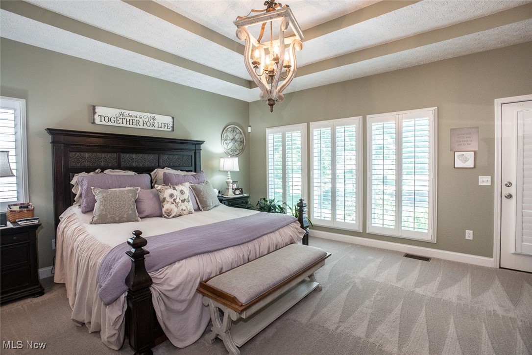 632 Rundle Street Lagrange, OH 44050 - Photo 11 of 30 Bedroom featuring a tray ceiling, light colored carpet, multiple windows, and a chandelier