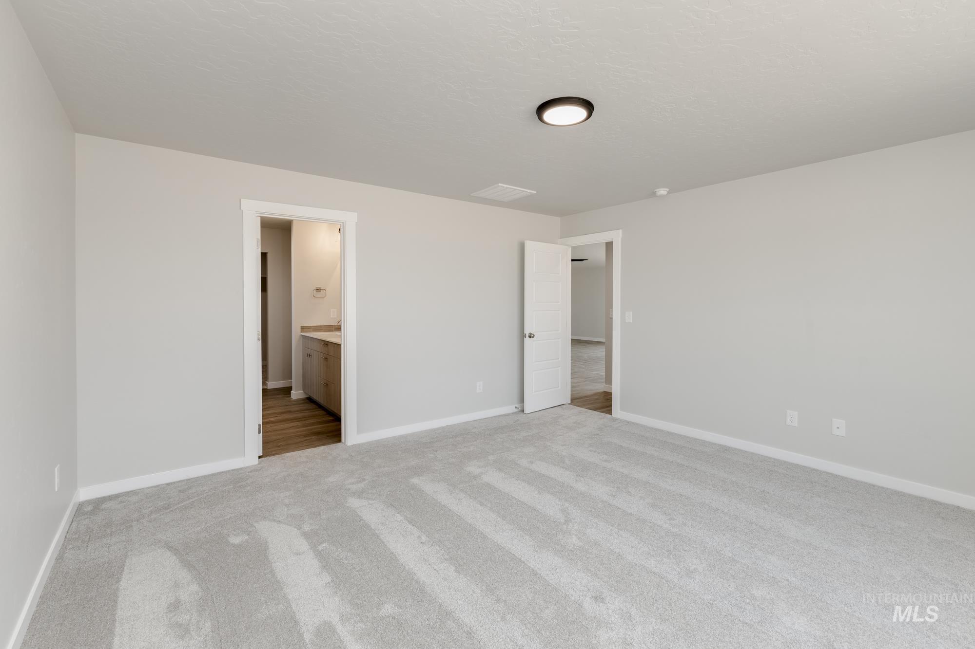 5315 Castleton Avenue Nampa, ID 83686 - Photo 17 of 19 Unfurnished bedroom featuring light carpet, connected bathroom, and a textured ceiling