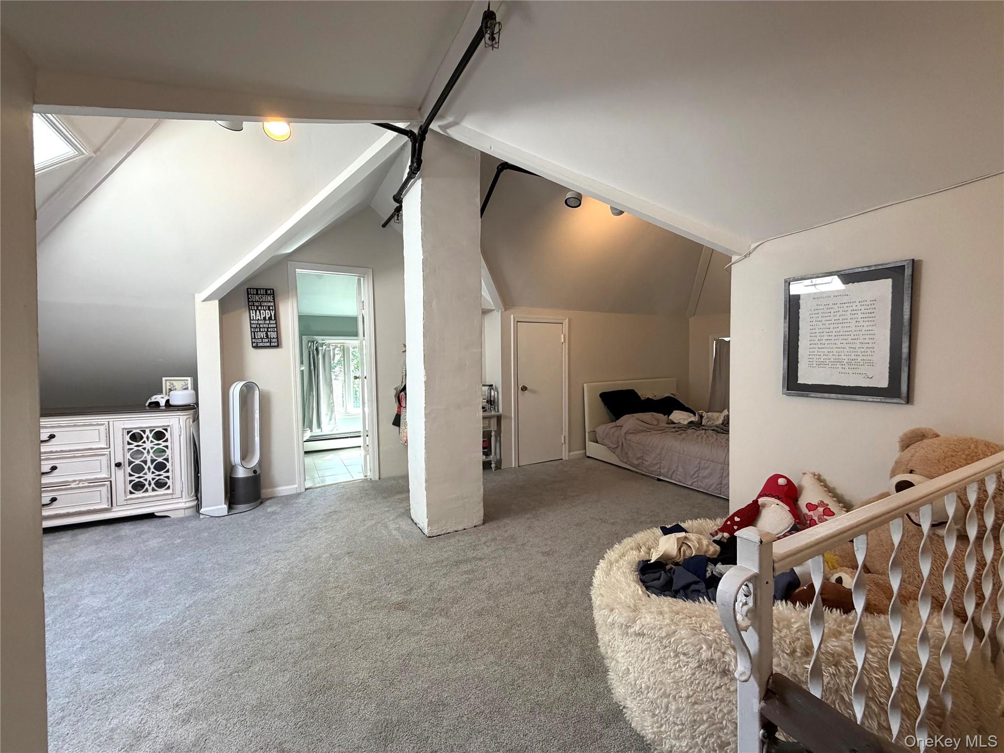 149 Fort Salonga Road Northport, NY 11768 - Photo 10 of 23 Carpeted attic space featuring sloped ceilings, white painted walls, and an exposed structural beam