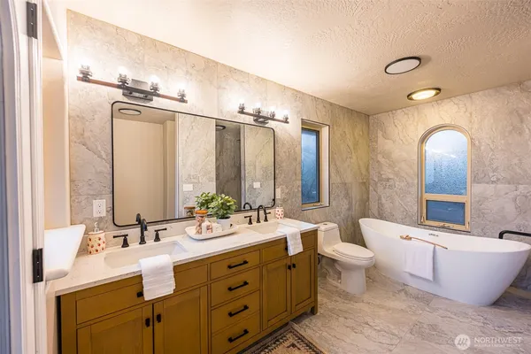a bathroom with double vanity sinks a large mirror and a bathtub