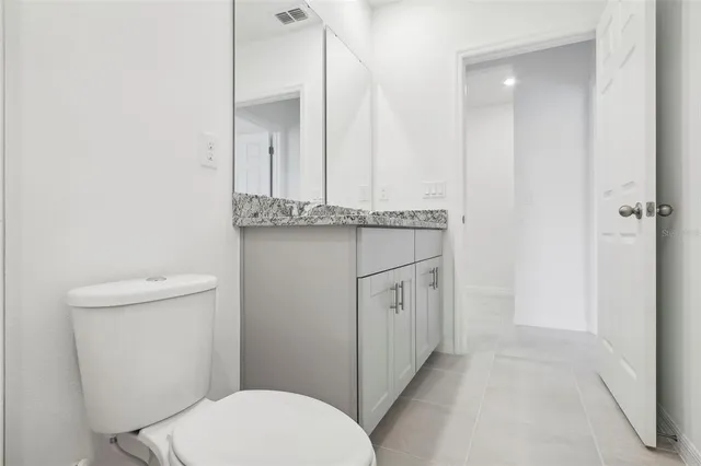 a bathroom with a granite countertop toilet a sink and a mirror