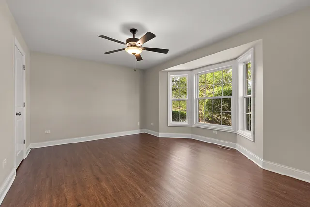 an empty room with wooden floor and a ceiling fan