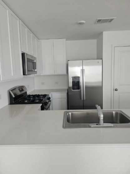 2218 Cumulus Court Lockhart, TX 78644 - Photo 15 of 35 a kitchen with stainless steel appliances granite countertop a refrigerator and a sink