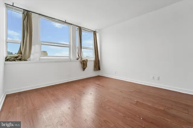 an empty room with wooden floor and windows
